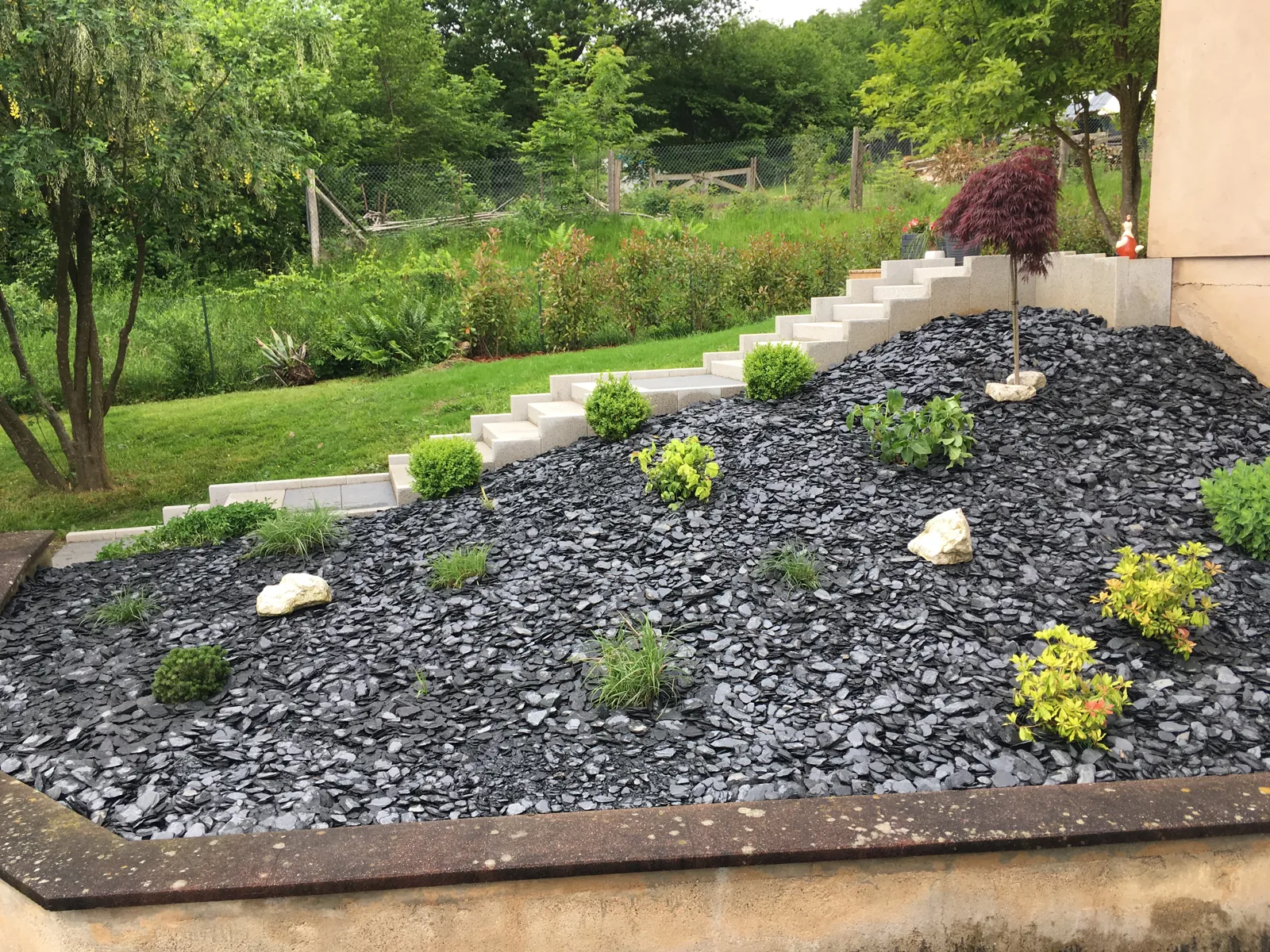 Massif planté et paillage minéral dans un jardin à Wisches